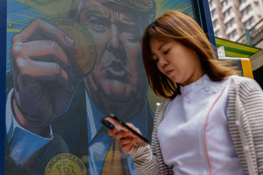 An illustration featuring U.S. President-elect Donald Trump holding Bitcoin is displayed outside a cryptocurrency exchange...