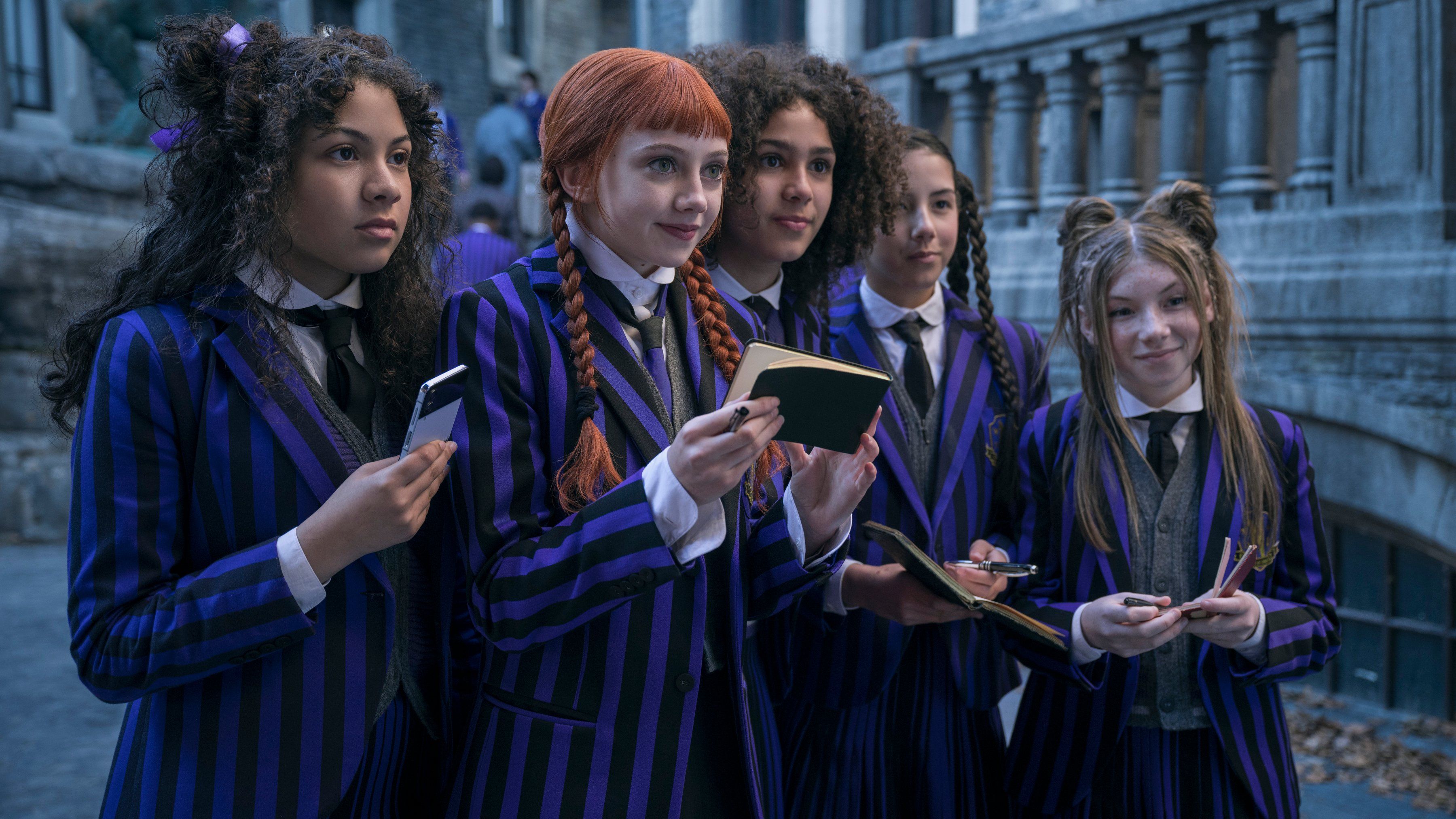 Evie Templeton as Agnes DeMille stands with other Nevermore students looking for autographs in Wednesday