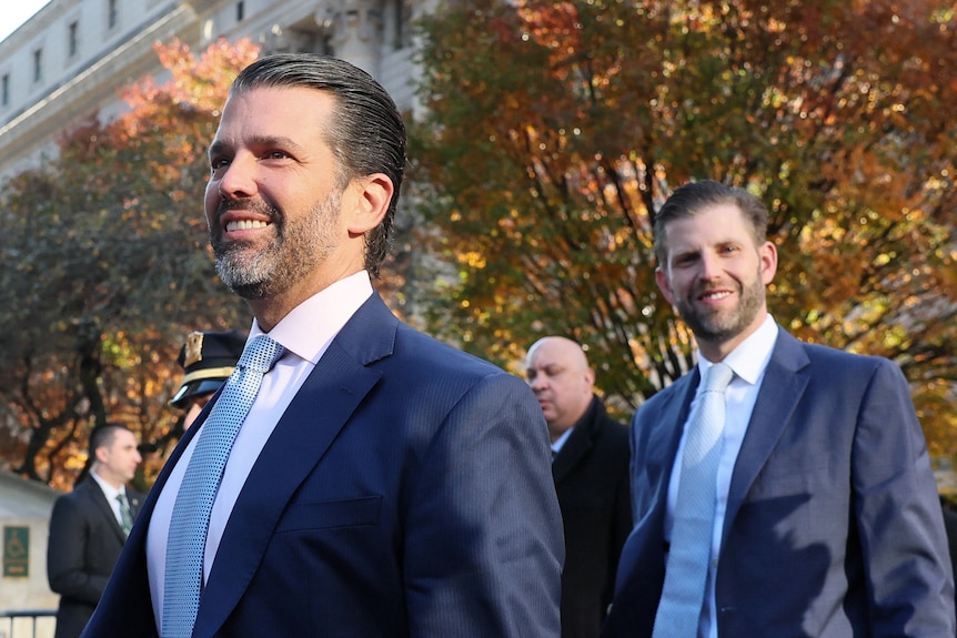 Donald Trump and Eric Trump smiling against a natural backdrop.
