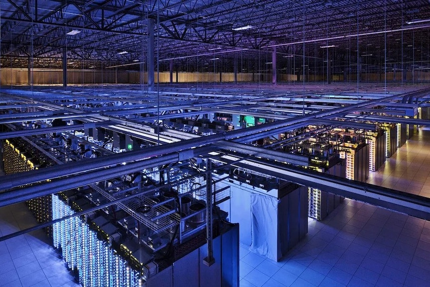 The interior of a large warehouse filled with server racks.
