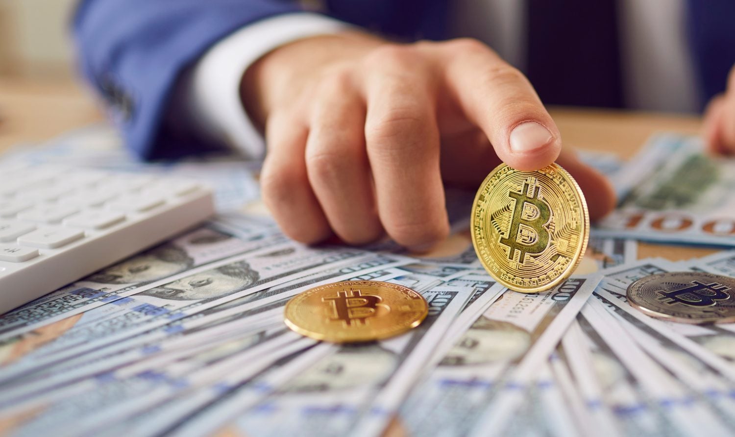A close-up of a shiny Bitcoin on US dollar bills held by an entrepreneur, symbolizing market transactions.