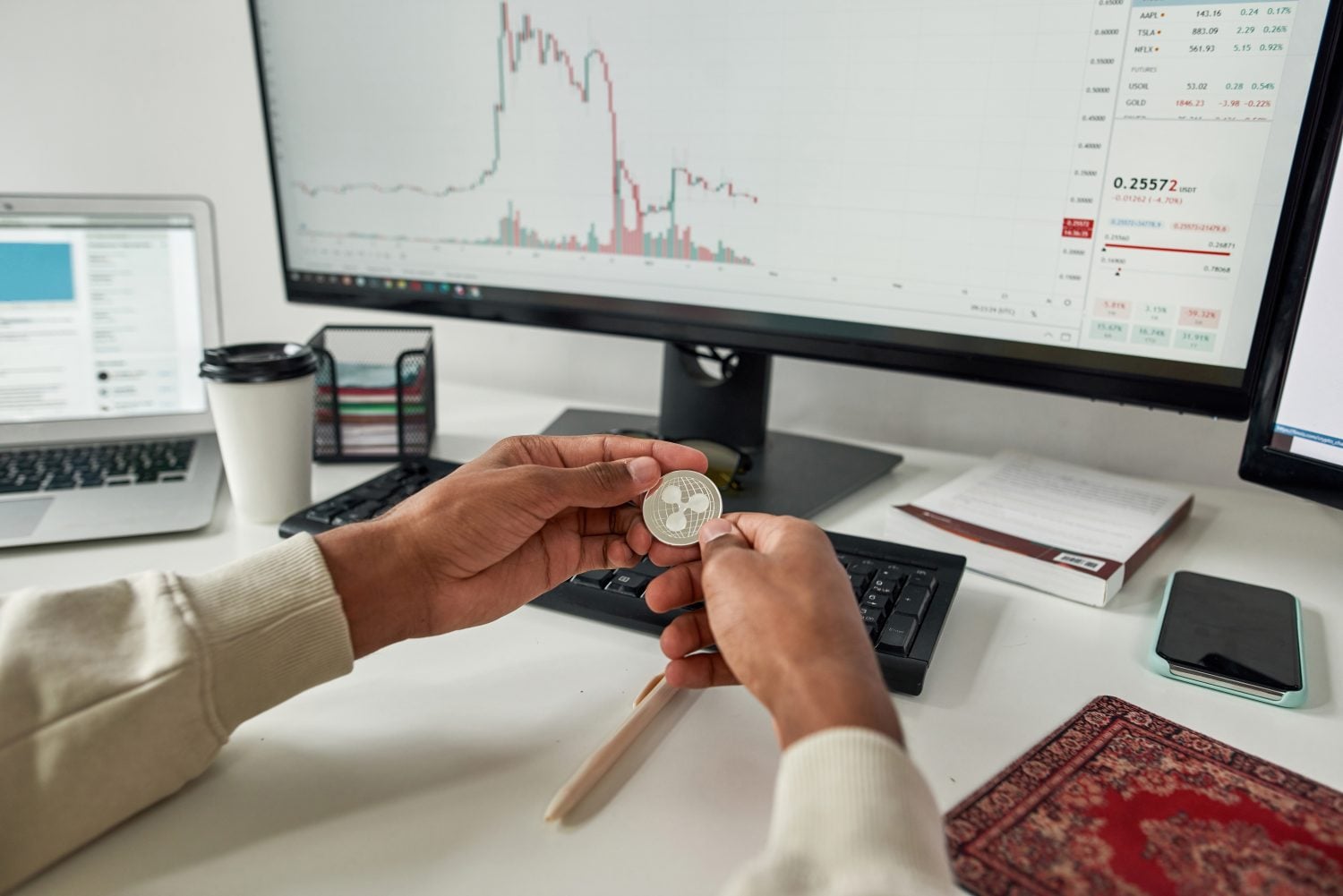 Hands of male trader holding Ripple XRP cryptocurrency token, investing in stock market to exchange it while trading using pc from home. Selective focus